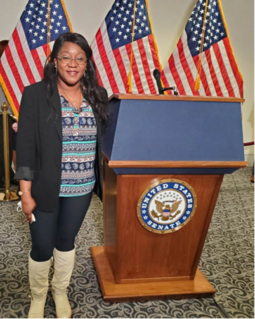 A woman stands next to a lectern bearing the U.S. Senate seal