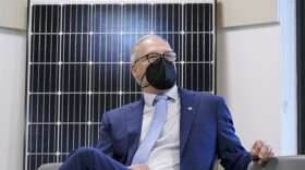 Washington Gov. Jay Inslee sits in front of a solar panel.