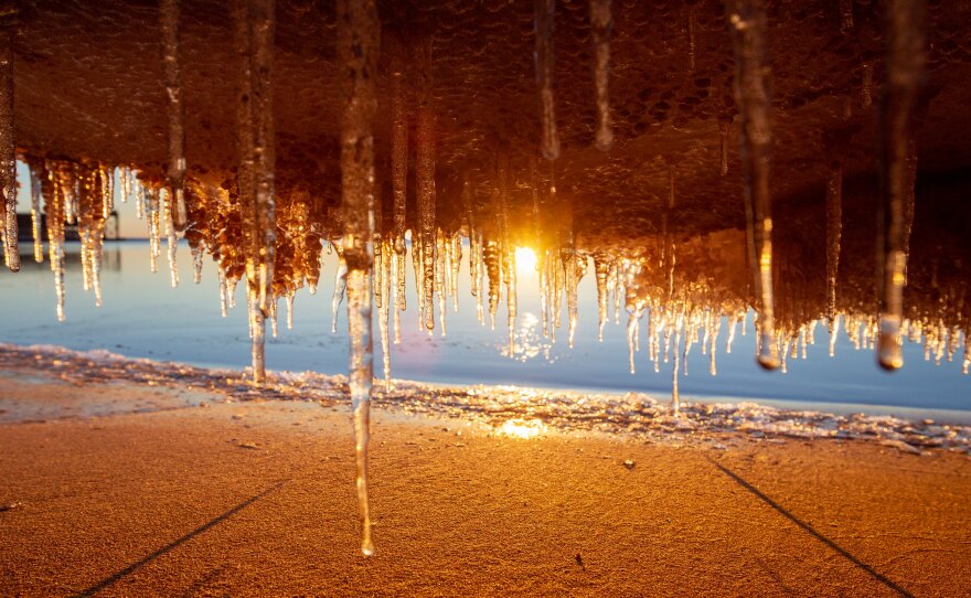 A sunset over the lake as seen through overhang of icicles 