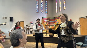 Two women sing while a band plays in the background.