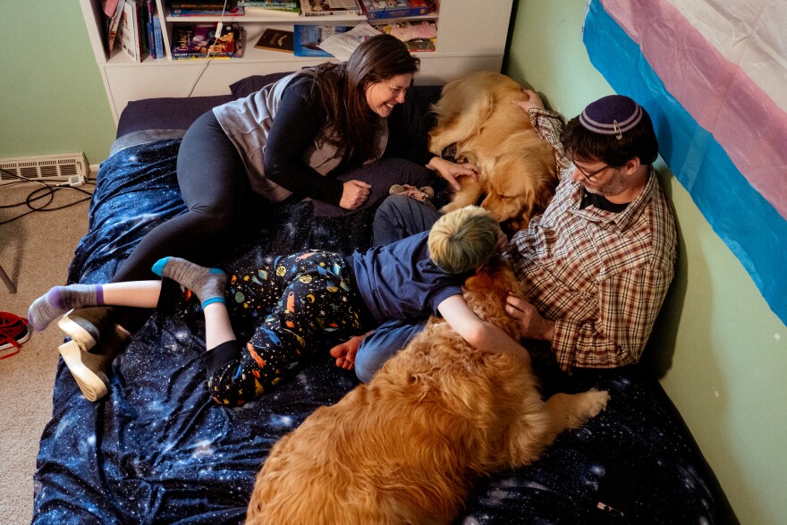 Rabbis Karen and Daniel Bogard and their 9-year-old son (center) embraces the family’s Golden Retrievers — Elvis and Violet — on Wednesday, March 22, 2023, at their home in St. Louis County. The Bogard’s son is one of the transgender Missourians who has been targeted by anti-trans policies, rhetoric, and legislation.