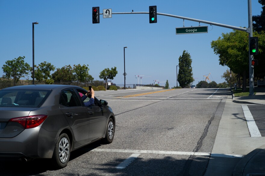 A man takes a photograph of a Google street sign at its headquarters in Mountain View.