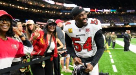 Football player on the field with family behind a black rope separating the two 