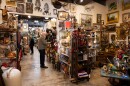 People look at objects in a store that is crowded with antique looking items.