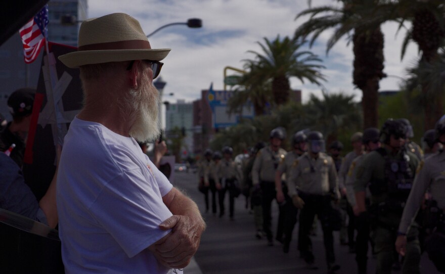 A man watches Las Vegas police officers assemble in front of the the Lloyd George Courthouse for the “No Kings”, on Saturday, June 14, 2025, in Las Vegas.
