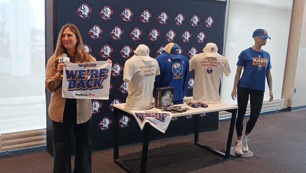 Buffalo Sabres Vice President of Marketing Cara Murphy displays a towel that will be placed on seats inside KeyBank Center for Game One of the Sabres-Bruins playoff series Sunday. Behind her are some of the new playoff merchandise that will be sold.