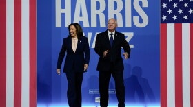 Kamala Harris (left) and Tim Walz (right) walk on a stage at a campaign rally.