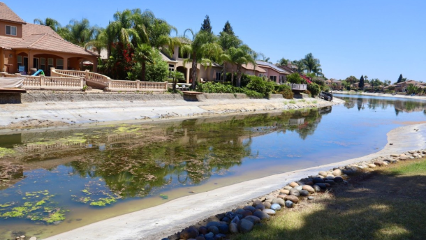 One of the lakes in Greenhills Estates sits at a significantly reduced water level on July 17, 2026, with algae spreading across the surface.