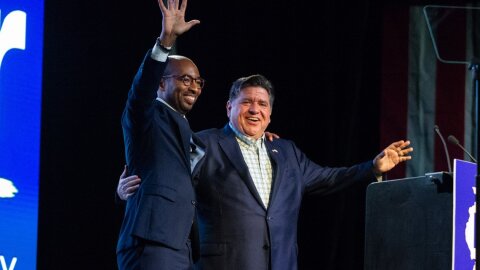 Gov. JB Pritzker, right, is joined by his running mate Christian Mitchell on stage at the Illinois Democratic County Chairs’ Association brunch in Springfield on Aug. 19, 2026.