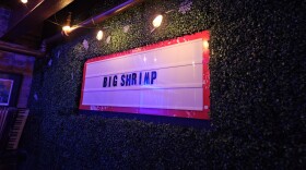 Big Shrimp on a marquee set on a wall covered in fake vines