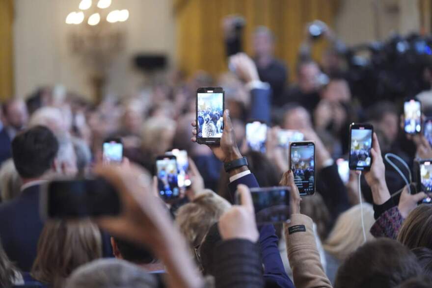 Personal cameras photograph President Donald Trump as he arrives to speak before signing an executive order barring transgender female athletes from competing in women's or girls' sporting events, in the East Room of the White House, Wednesday, Feb. 5, 2025, in Washington. (Evan Vucci/AP)