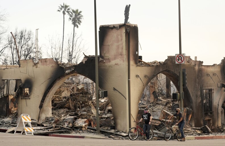 Cyclists move past a destroyed structure on Lake Avenue, Thursday, Jan. 9, 2025, in Altadena, Calif.