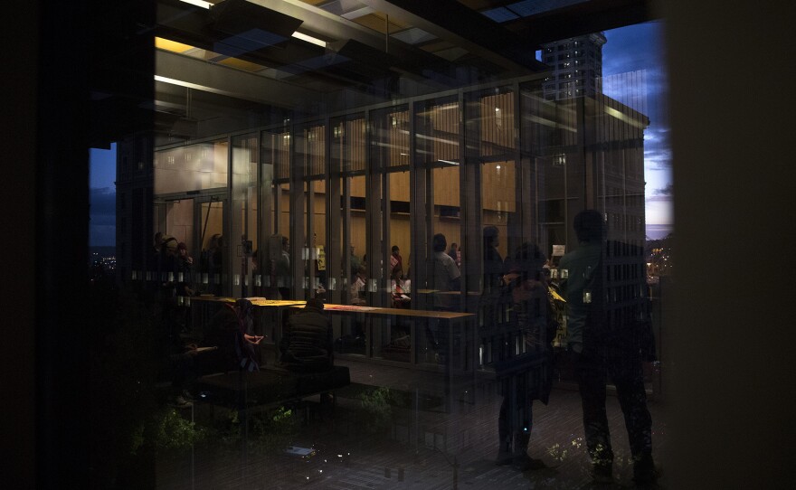 A crowd is reflected in the window of City Hall during the public hearing on Wednesday, November 1, 2017, in Seattle. 