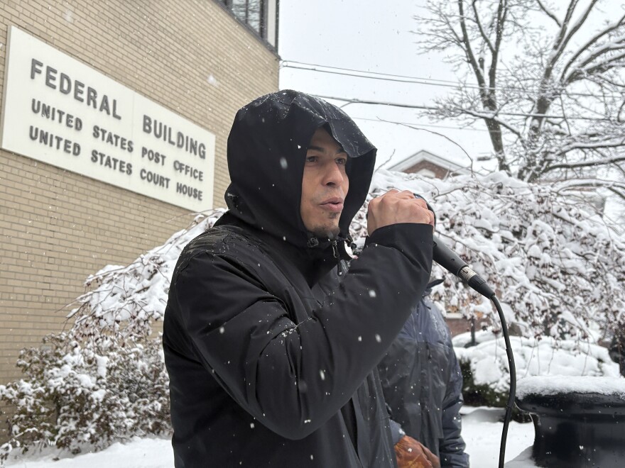 A man with a microphone speaks to a crowd outside of the federal courthouse in Burlington