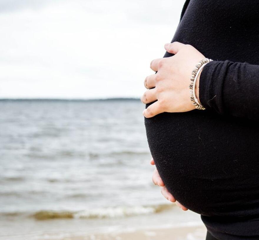 A side view of a woman's pregnant belly