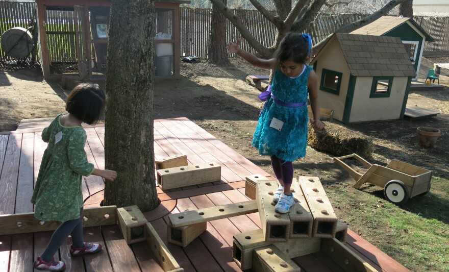 One child's stage is another student's obstacle course. Preschoolers at Bing Nursery School play with outdoor blocks.