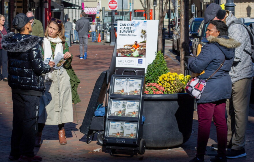  A woman shares Jehovah's Witnesses' literature with a passerby on a street corner