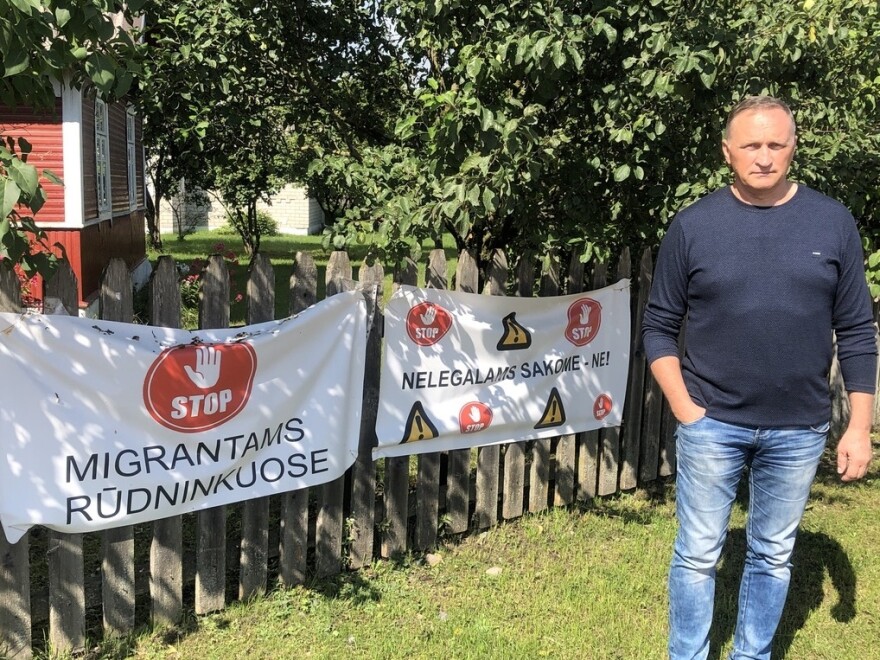 Rudninkai Mayor Gennadi Baranovich stands in front of a banner demanding that asylum seekers not be allowed near the town.