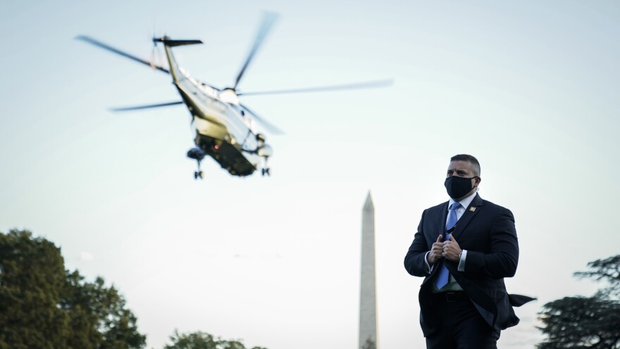 A U.S. Secret Service agent stands on the South Lawn of the White House as Marine One, with the president on board, leaves Friday for Walter Reed.