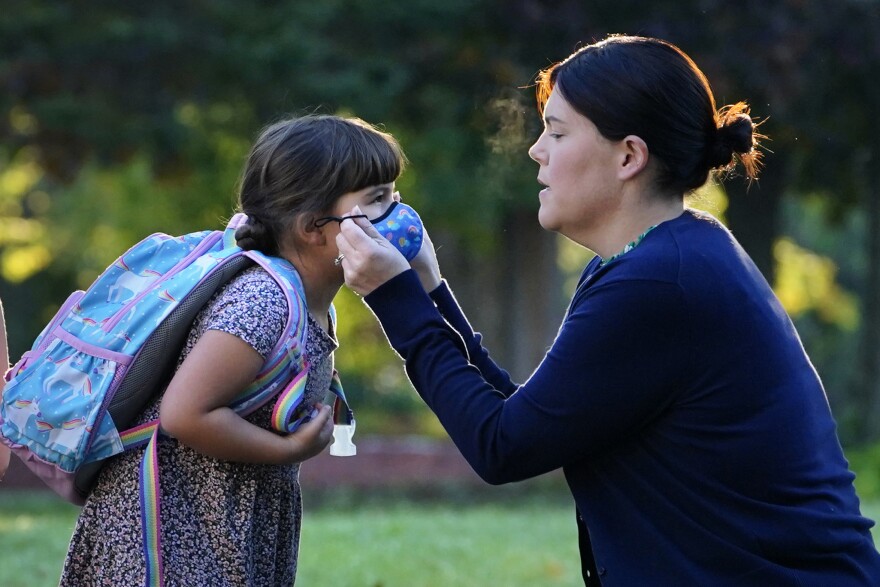 Sarah Staffiere adjusts a face covering on her daughter, Natalie, before school, Thursday, Oct. 7, 20211, in Waterville, Maine. Staffiere, a senior laboratory instructor at Colby College, said she will be relieved when her two children can be vaccinated.