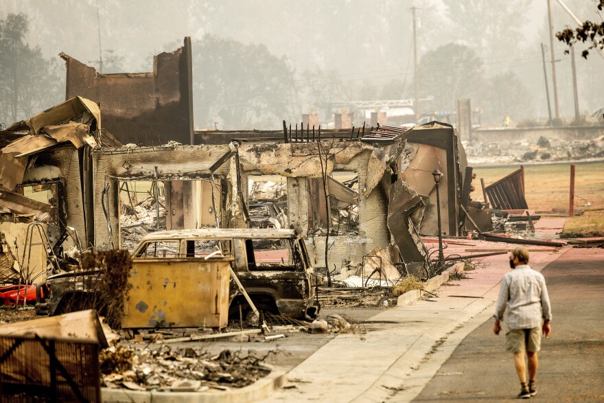 A man walks near residences destroyed by the Almeda Fire in Talent, Ore., on Sept. 16, 2020. As wildfires burn more homes, more people will turn to FEMA for aid.