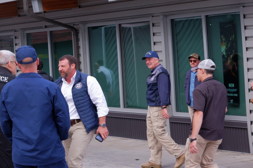 Secretary of Homeland Security Markwayne Mullin shakes hands with a police officer outside of the Kodiak Marketplace on August 11 as Sen. Dan Sullivan walks beside him.