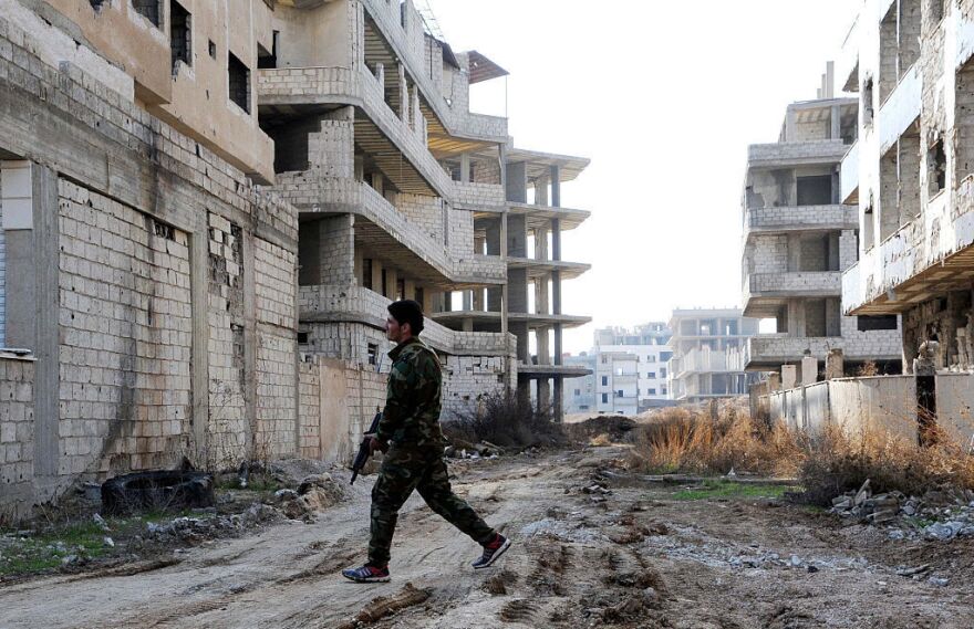 A Syrian soldier walks on a ravaged street in Daraya, a besieged suburb of Syria's capital, in February.