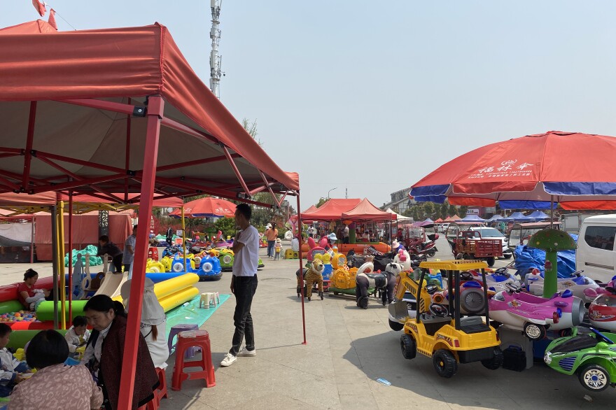 Lou Beiling, relocated from a remote village to Qizingguan, now works in this market outside the compound.