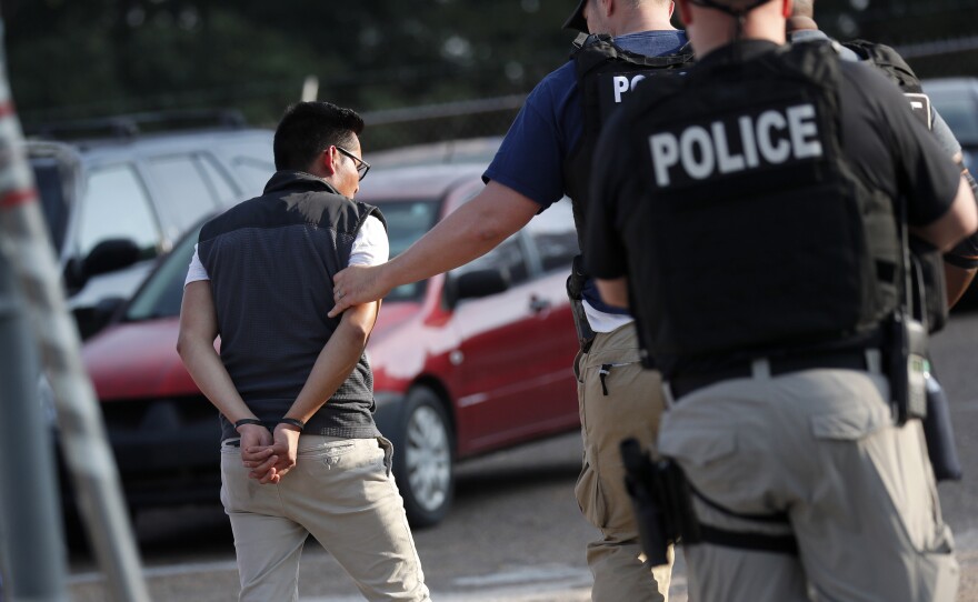A man is taken into custody at a Koch Foods plant in Morton, Miss., on Aug. 7. U.S. immigration officials raided several Mississippi food processing plants and signaled that the early-morning strikes were part of a large-scale operation targeting owners as well as employees.