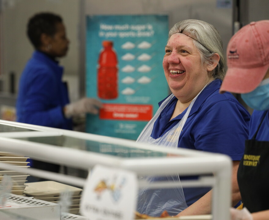 Debbie Lane, a food service employee at West Irondequoit Central School District, welcomes students to pick out a meal for lunch at Dake Junior High School.