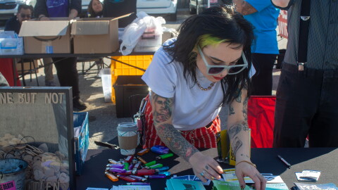 A Shred the Stigma employee arranges harm reduction supplies on a table outside the Oklahoma City Homeless Alliance Day Shelter on Thursday, Oct. 22. The nonprofit was one of several healthcare organizations at a free health and wellness fair for people experiencing homelessness.