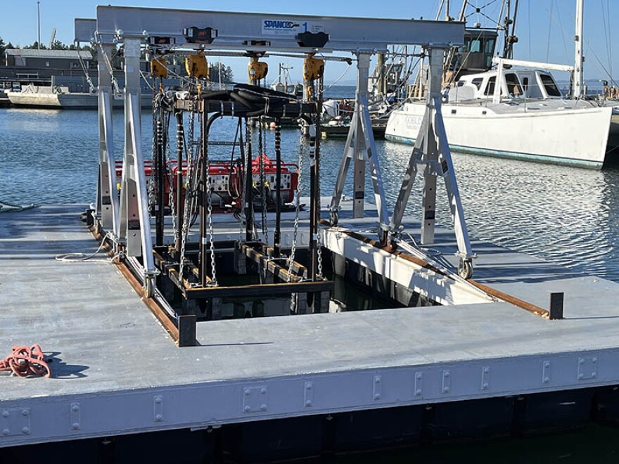 A floating platform that holds four vibrating heads on wands is docked at a marina.