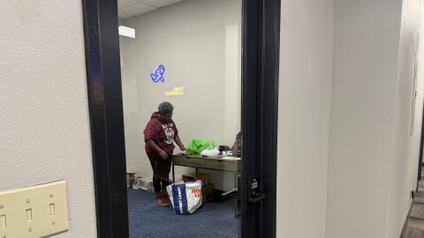A woman in an almost empty office unpacking newspapers from a bag.