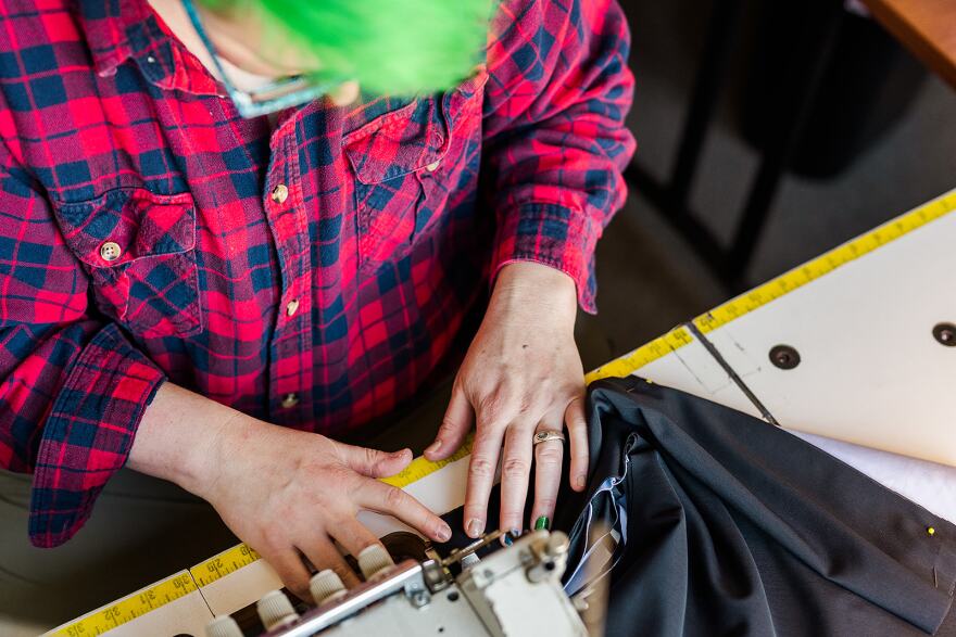 A person sewing fabric through a sewing machine.