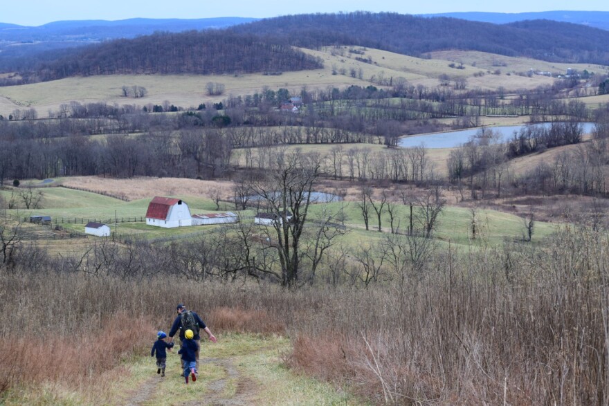 A man is running in a field with two children.S