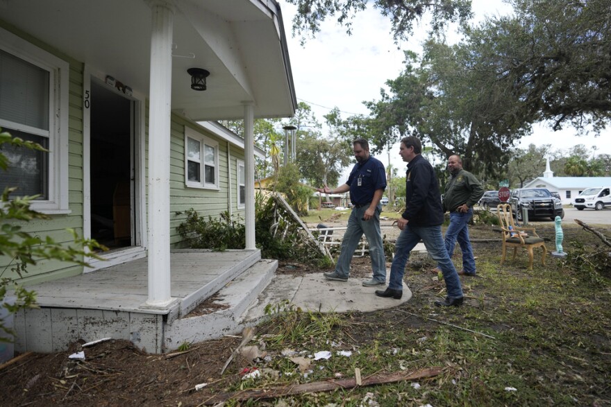 Two men walk into a damaged home.