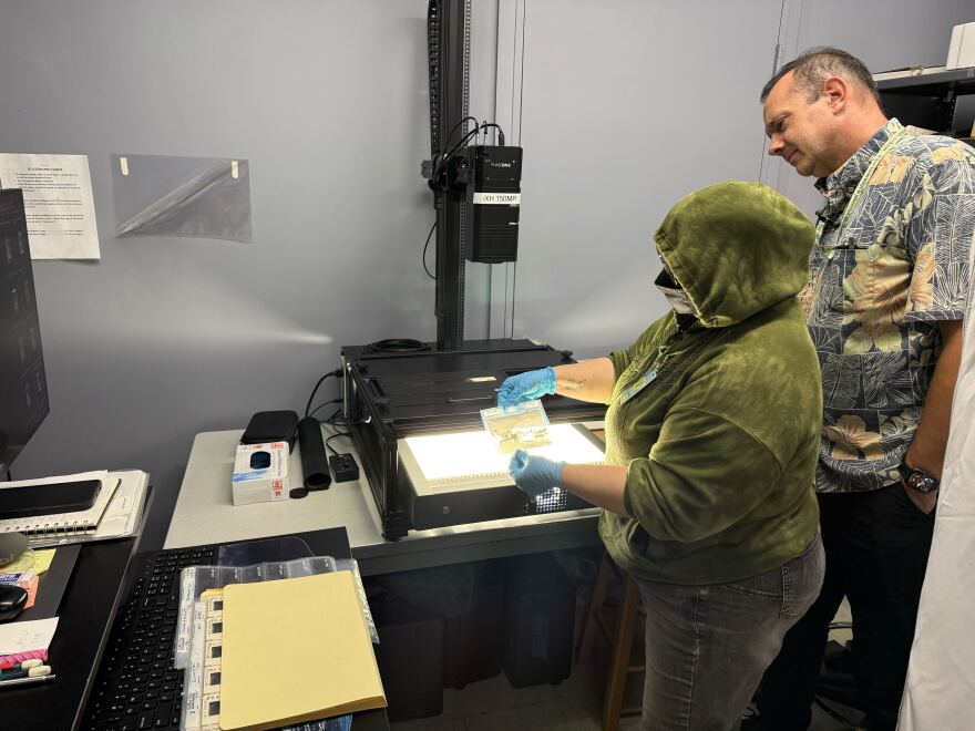A digitization specialist, left, and State archivist Adam Jansen scan a photo of Punahou School's Dillingham Theater. ( Sept. 5, 2025)