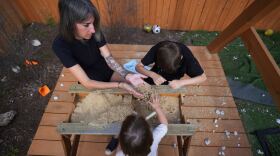 Eileen Lamb, left, who along with her son Charlie Lamb, has autism, works with her son and daughter Billie, bottom, at their home, Monday, May 12, 2025, in Austin, Texas. (AP Photo/Eric Gay)