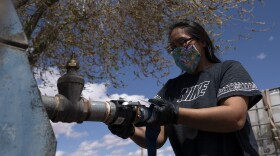 Raynelle Hoskie attaches a hose to a water pump to fill tanks in her truck outside a tribal office on the Navajo reservation in Tuba City, Ariz., on April 20, 2020.