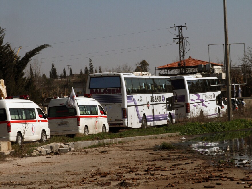 Syrians on two buses followed by the Syrian Arab Red Crescent's vehicles evacuate Syria's battleground city of Homs, on Friday.