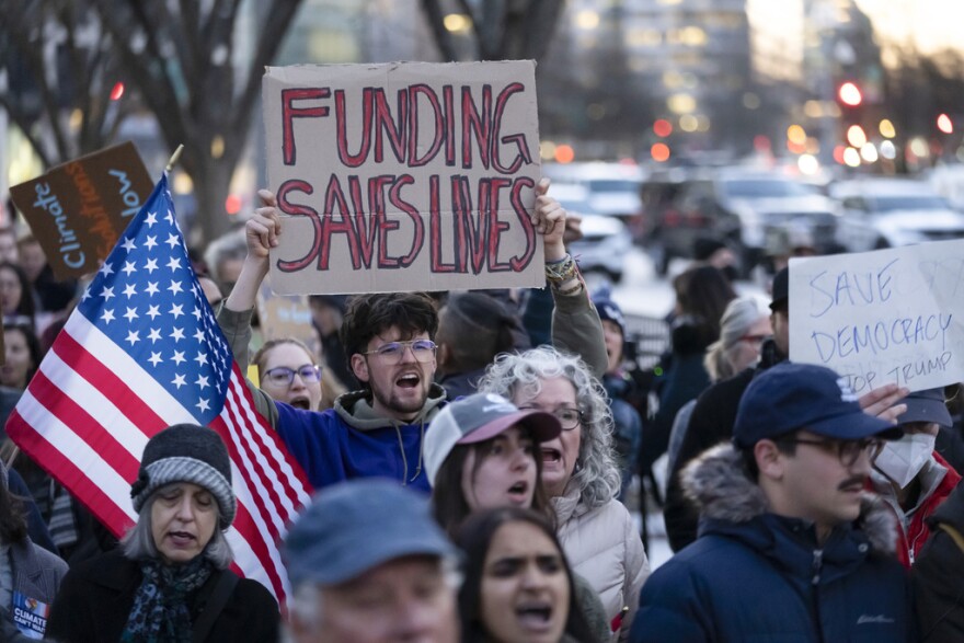 People protest against a funding freeze of federal grants and loans following a push from President Donald Trump to pause federal funding near to the White House in Washington, Tuesday, Jan. 28, 2025.