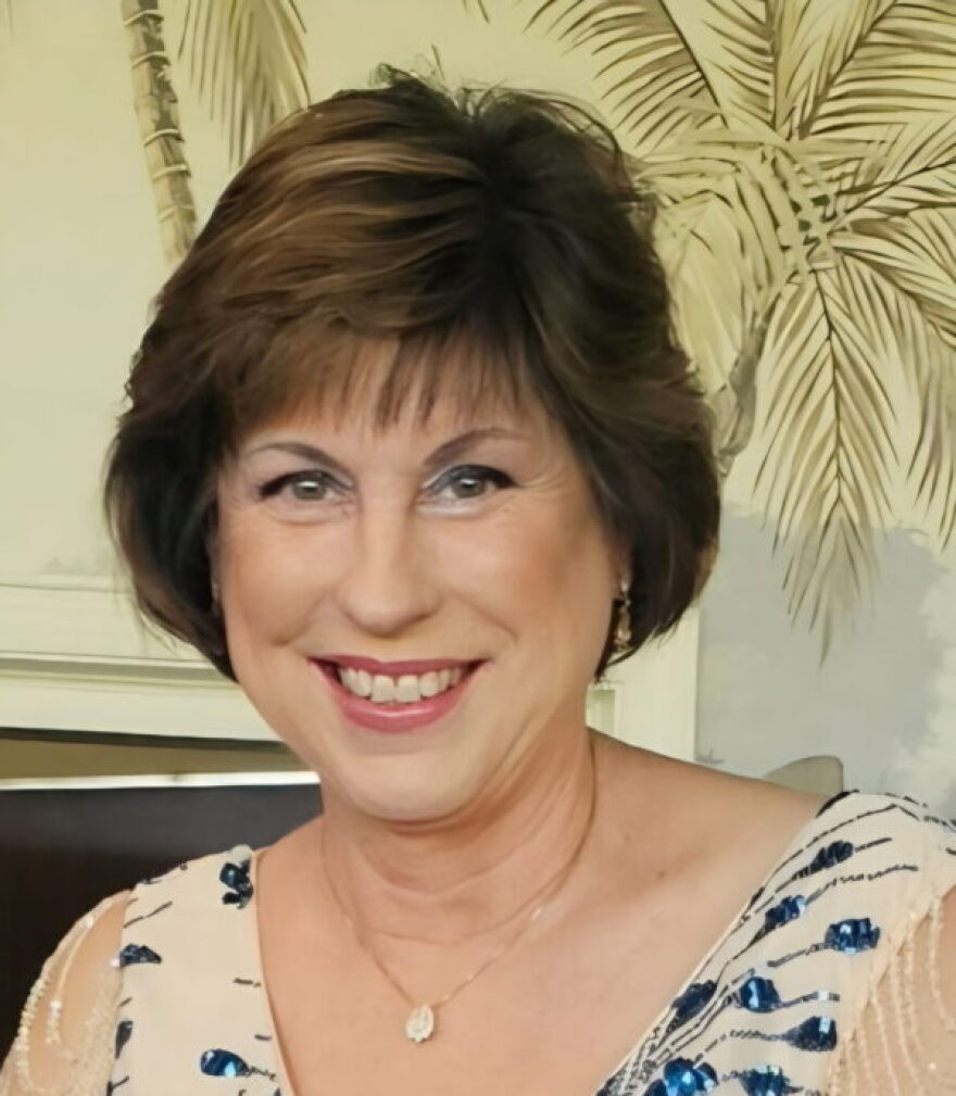 A woman with ear length brown hair smiling into the camera.