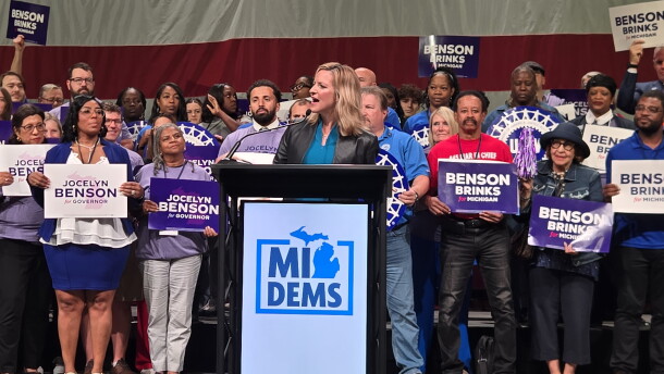 Michigan democratic gubernatorial candidate Jocelyn Benson stands in front of a podium with a Michigan Democrats sign on it. She is in front of a large crowd at the 2026 Michigan Democratic Convention. 