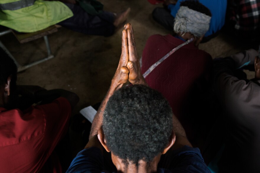 A man holds his hands together in prayer at the reconciliation meeting in Henganofi.