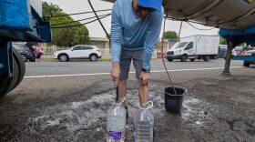 A man fills water jugs from a tanker truck amid drought-driven water rationing, in the Cupey sector of San Juan, Puerto Rico, Wednesday, Aug. 5, 2026.