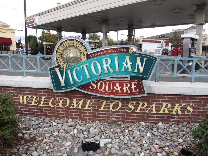 A sign says City of Sparks with a gas station behind it.