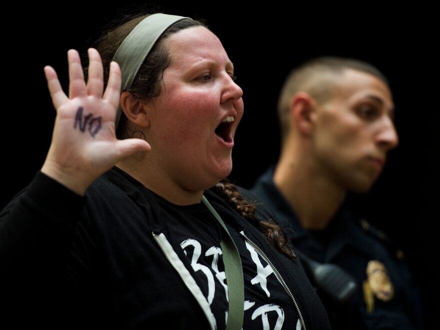 A demonstrator raises her hand, on which the word "no" is scrawled in black. She was one of many demonstrators clad in black who packed the Hart building Thursday in protest of Kavanaugh's nomination.