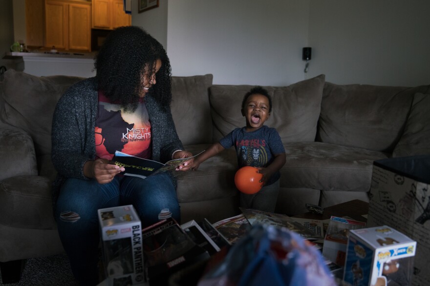 Stephanie Williams and her son Micah, 2, sit on the sofa looking at comic books in their living room in Charlotte, N.C.