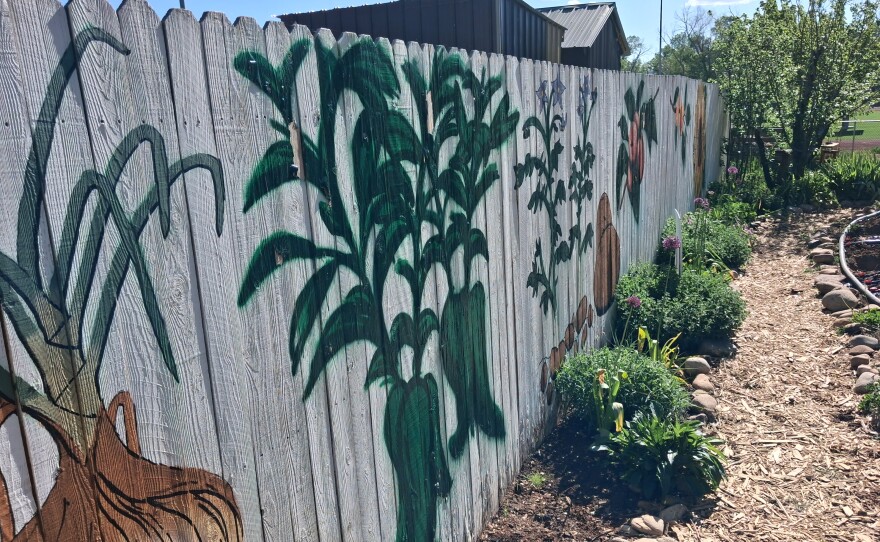 A mural-painted fence surrounds part of the Mancos School Garden.