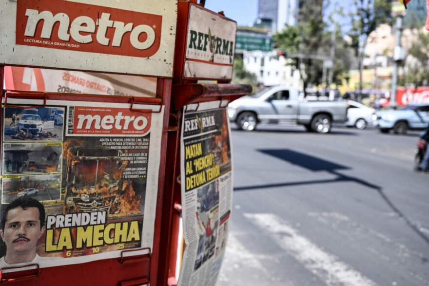 The front page of a local newspaper displays news about the death of Nemesio Oseguera, alias "El Mencho," Mexico's most wanted drug lord in recent years, in Mexico City on February 23, 2026. Mexico has deployed 10,000 troops to quell clashes sparked by the killing of the country's most wanted drug lord, which have left dozens dead, officials said on February 23. Nemesio "El Mencho" Oseguera, leader of the Jalisco New Generation Cartel (CJNG), was wounded on February 22 in a shootout with soldiers in the town of Tapalpa in Jalisco state and died while being flown to Mexico City, the army said. (Photo by Yuri Cortez/AFP via Getty Images)